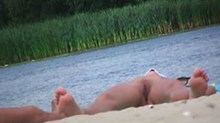 Wide spread pussy lying on a beach in this spy cam video