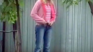 Blonde girl in tight jeans pants peeing outdoors